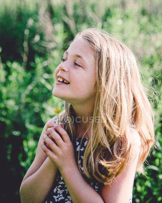Sorridente ragazza che tiene un ranuncolo — Foto stock