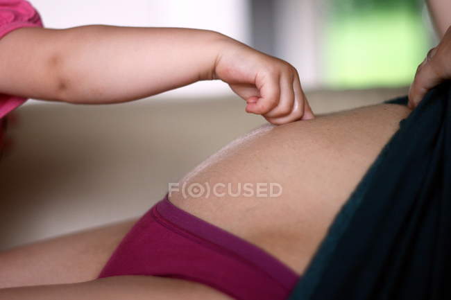 Mão do bebê tocando barriga — Fotografia de Stock
