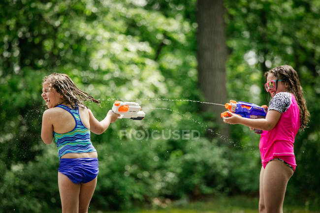 Two girls having  with water guns — Stock Photo
