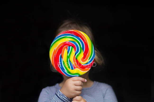 Girl holding multi-colored lollipop — Stock Photo