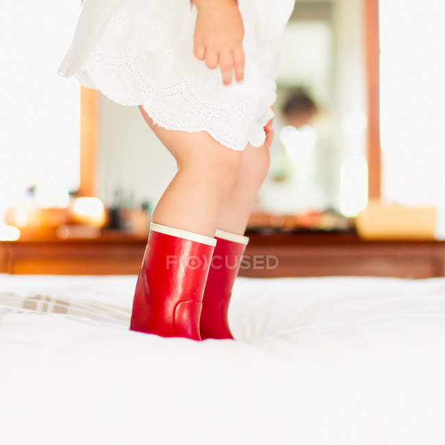 Fille en bottes rouges sur le lit — Photo de stock