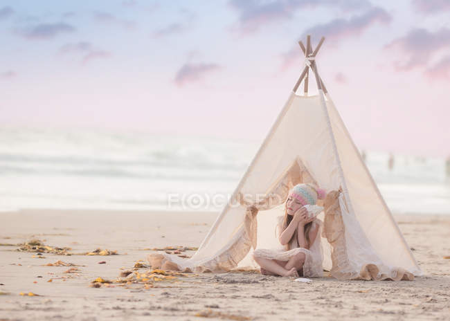 Девушка, сидящая в вигваме на пляже — стоковое фото