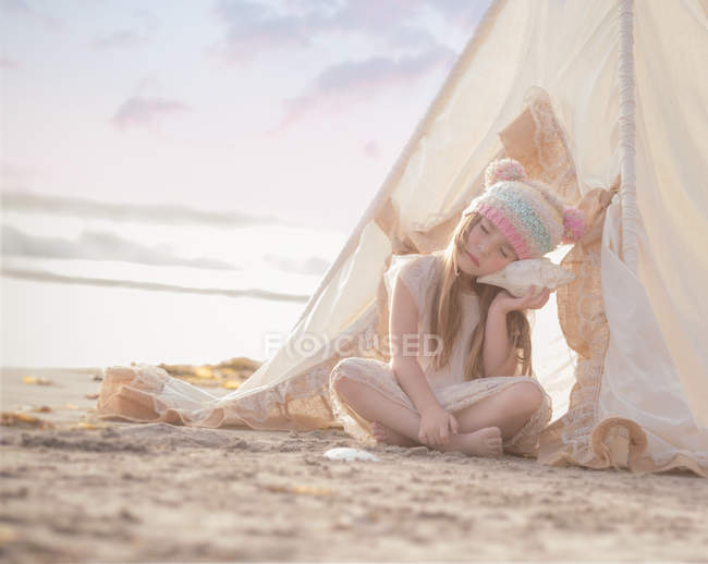 Fille assise dans wigwam sur la plage — Photo de stock
