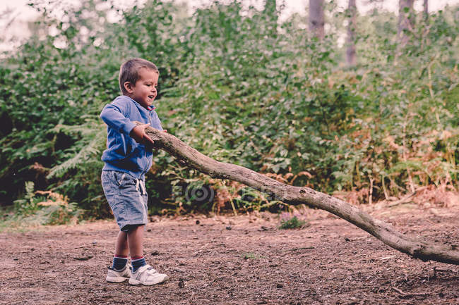 Boy inlifting  heavy log — Stock Photo