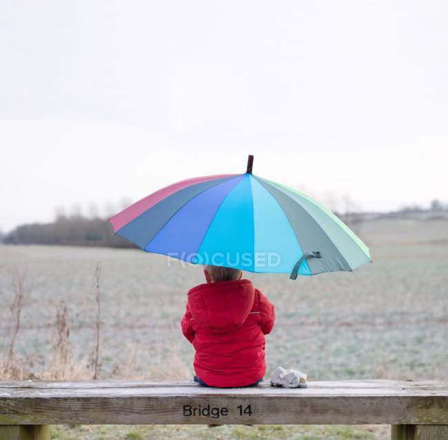 Junge mit Regenbogen auf Bank sitzend — Stockfoto