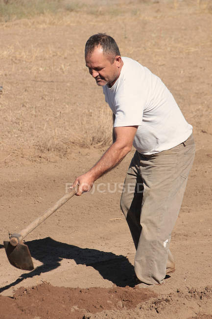 Man digging with garden hoe — Stock Photo