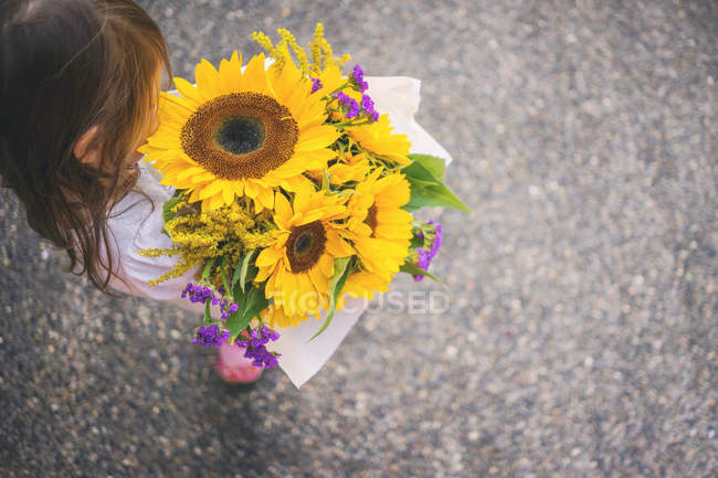 Mädchen mit Sonnenblumenstrauß — Stockfoto
