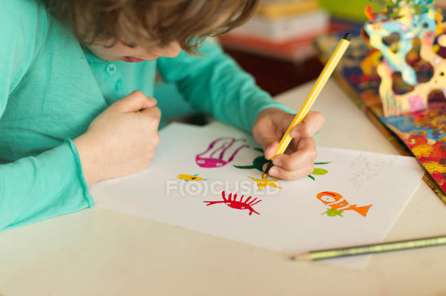 Niño sentado en un dibujo de mesa - foto de stock