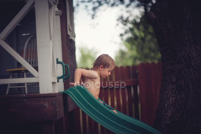 Niño en diapositiva en el patio trasero - foto de stock