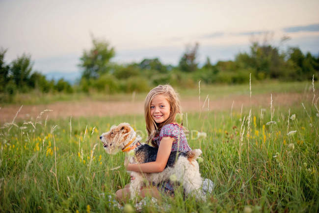 Menina abraçando seu cão terrier raposa — Fotografia de Stock