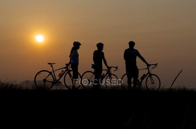 Silhouette of three cyclists — Stock Photo