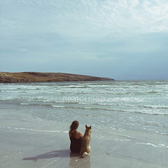Femme à la plage avec chien — Photo de stock