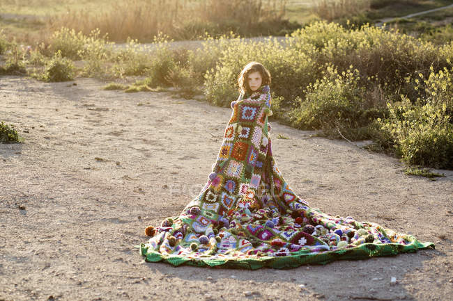 Girl wrapped in blanket in field — Stock Photo