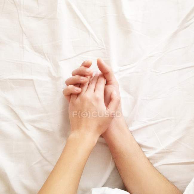 Couple lying in bed holding hands — Stock Photo