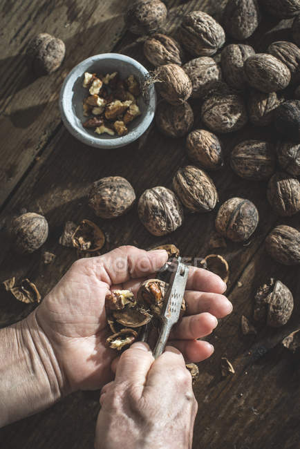 Женские руки, разбивающие грецкие орехи — стоковое фото