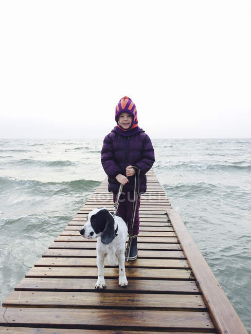 Ragazza e cane in piedi sul molo — Foto stock