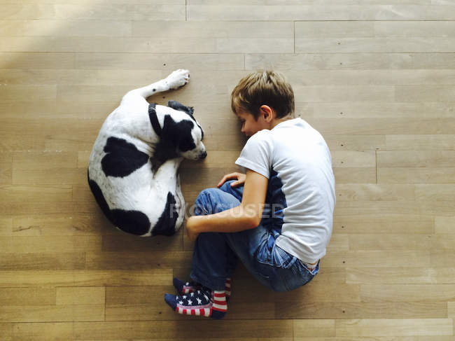 Хлопчик і собака лежать на підлозі — стокове фото