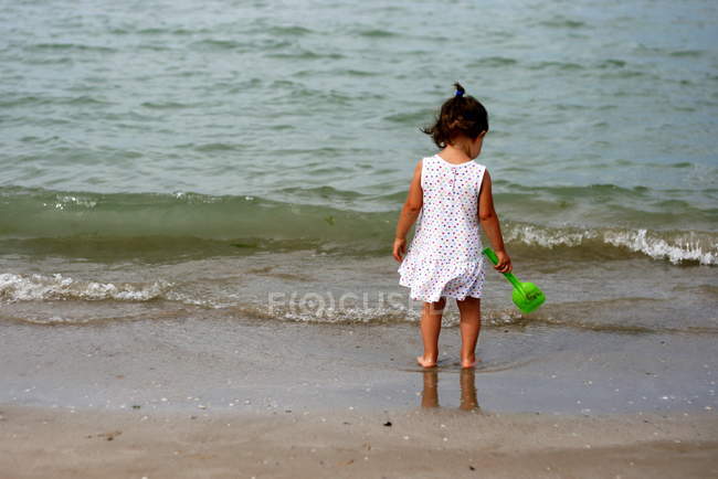 Petite fille debout sur la plage — Photo de stock