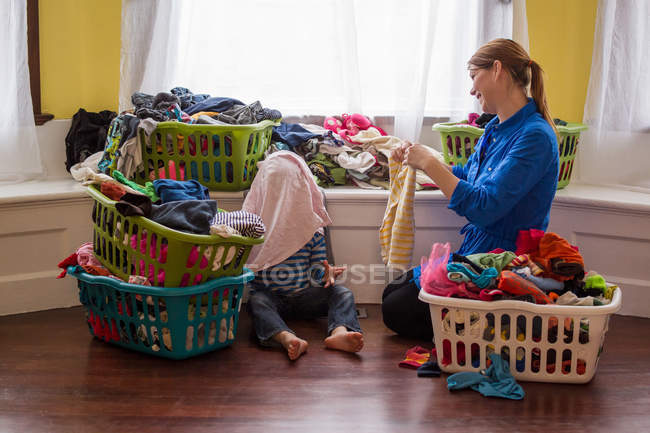 Madre con hijo rodeada de cestas de lavandería - foto de stock