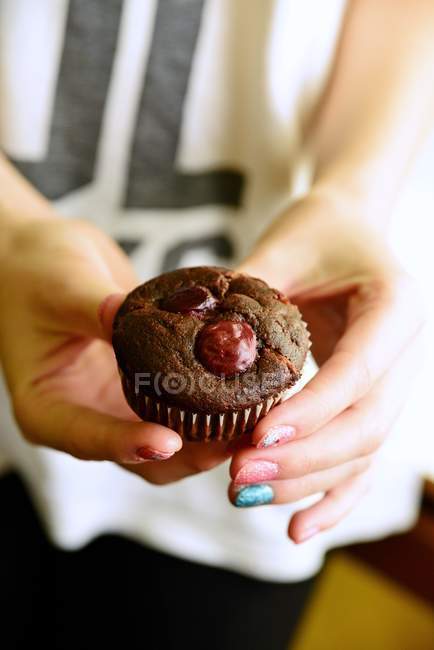Mulheres mãos segurando muffin de chocolate — Fotografia de Stock