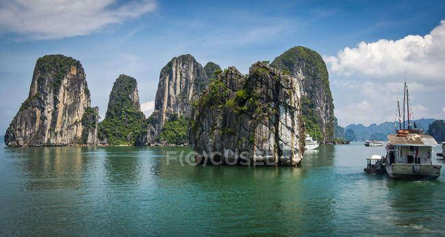 Barco en el agua rodeado de acantilados rocosos - foto de stock
