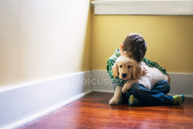 Boy hugging golden retriever puppy — Stock Photo