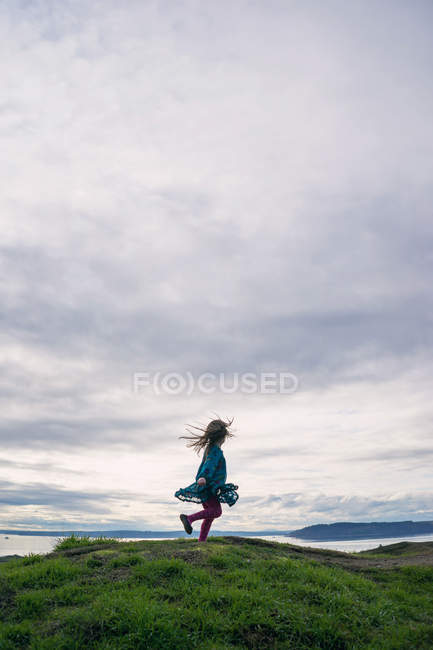 Girl spinning around on hill — Stock Photo