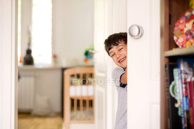 Sorrindo menino espreitando porta redonda — Fotografia de Stock