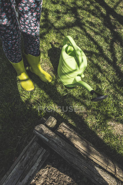 Mujer con botas y regadera en el jardín - foto de stock