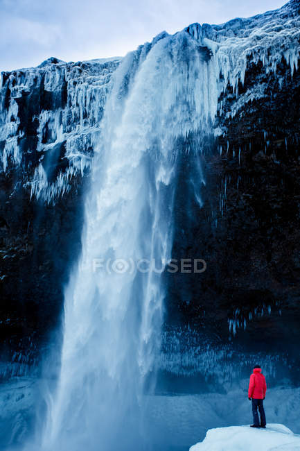 Uomo in piedi di fronte alla cascata — Foto stock