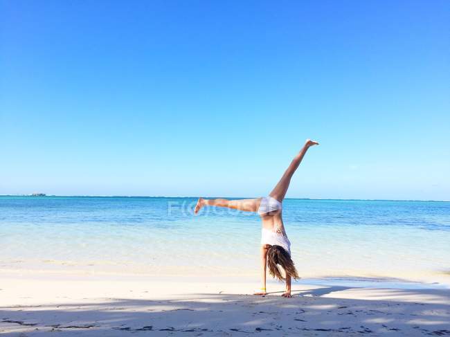 Chica haciendo handstand en playa - foto de stock