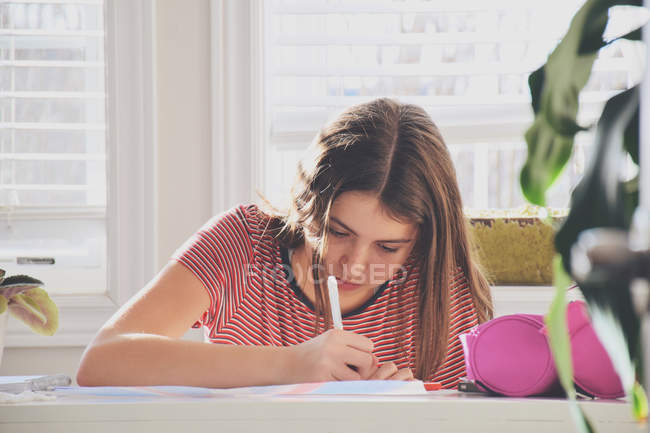 Девушка-подросток сидит за столом — стоковое фото
