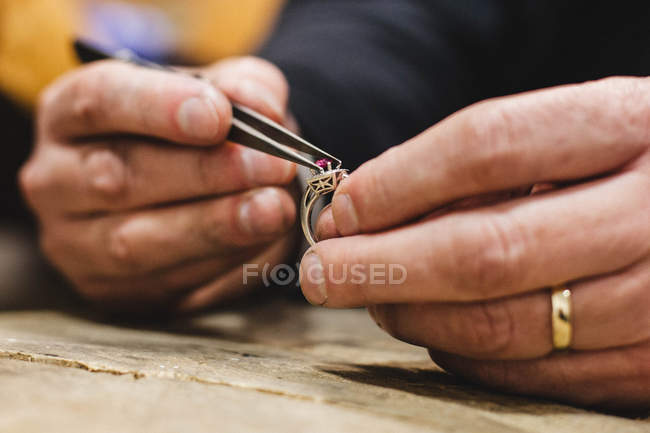 Jeweler mounting gemstone onto ring — Stock Photo