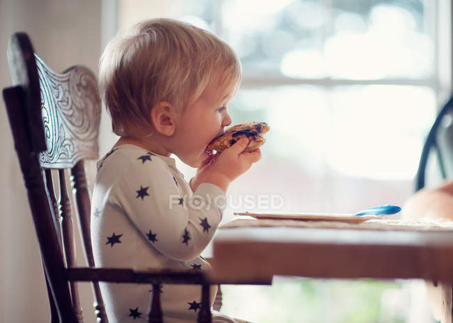 Мальчик сидит и ест блинчики — стоковое фото
