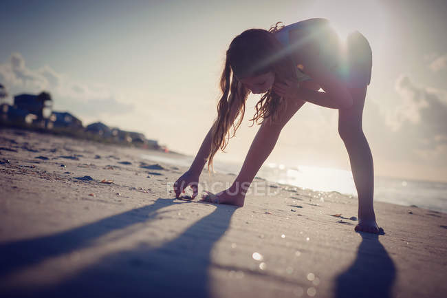 Girl looking for seashells on beach — Stock Photo