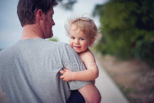 Padre llevando sonriente hijo - foto de stock