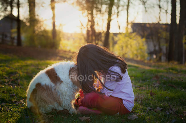 Chica sentada con perro en el jardín - foto de stock