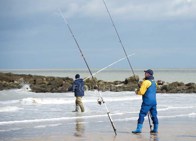 Hombres de pie en la pesca de playa - foto de stock