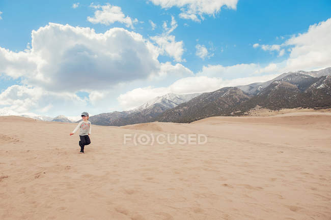 Мальчик бегает по большим песчаным дюнам национального парка — стоковое фото