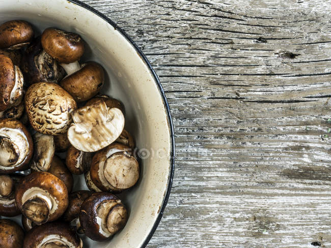 Bowl of raw mushrooms on wooden table — Stock Photo