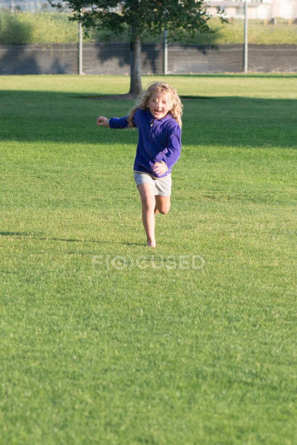 Menina corre na grama para a câmera — Fotografia de Stock