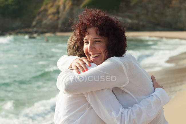 Duas mulheres abraçando na praia — Fotografia de Stock