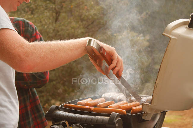 Человек готовит сосиски — стоковое фото