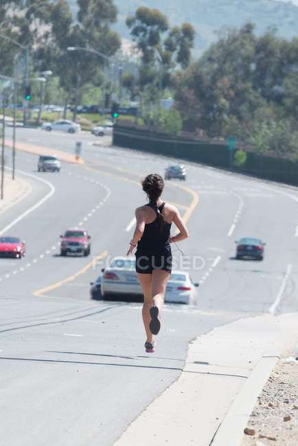 Donna che corre lungo la strada — Foto stock