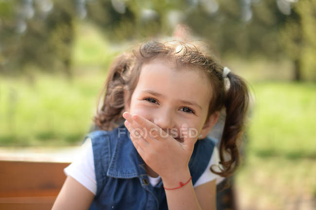 Chica cogida de la mano delante de la boca - foto de stock