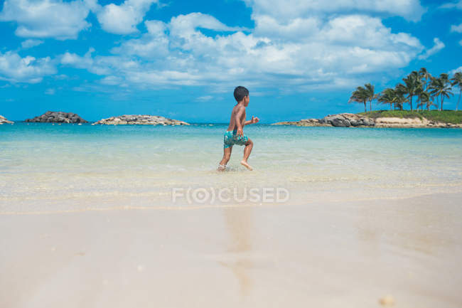 Junge rennt am Strand entlang — Stockfoto