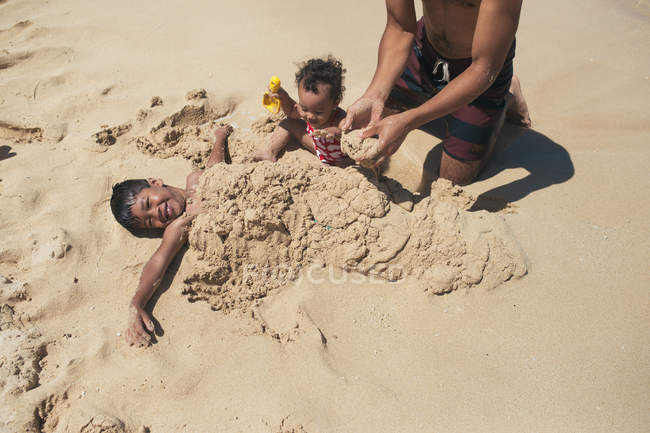 Pai e filhos brincando na areia — Fotografia de Stock