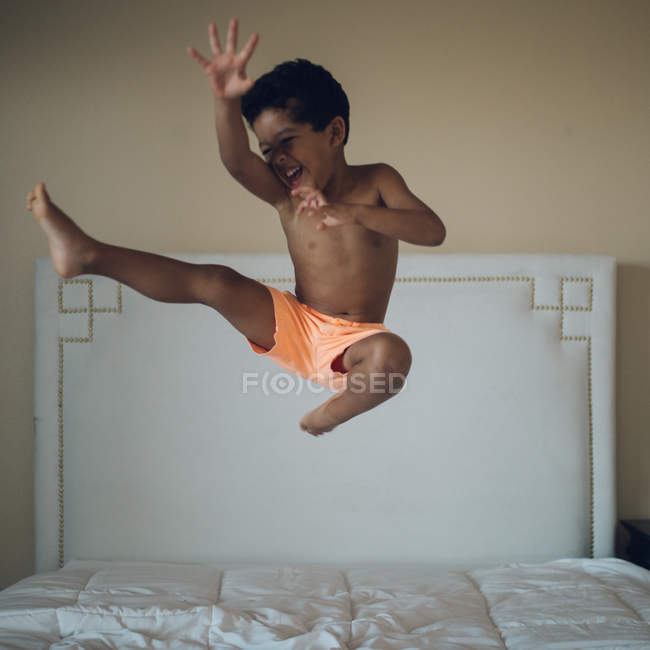 Boy jumping on bed in bedroom — Stock Photo