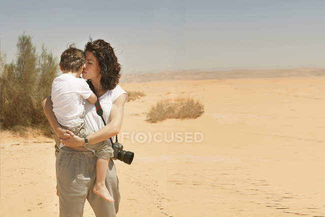 Mère debout dans le désert portant fils — Photo de stock
