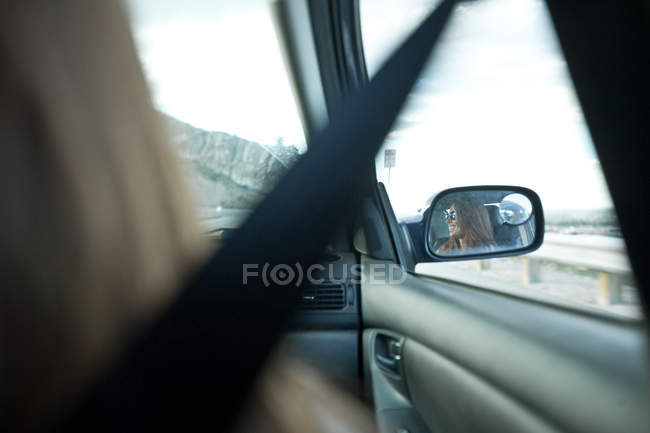 Riflessione della donna nello specchio auto — Foto stock